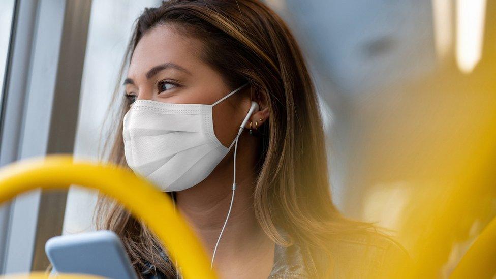 A woman in a face mask on a bus