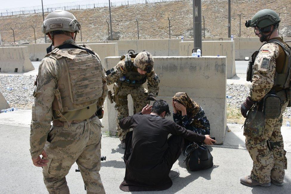 A woman buries her head in her hands at Kabul airport as thousands tried to gain access to flights.