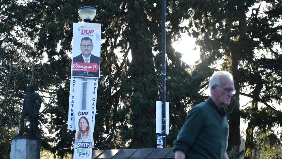 A man walk past election posters featuring the DUP and TUV in Hillsborough on April 28, 2022 in Belfast, Northern Ireland