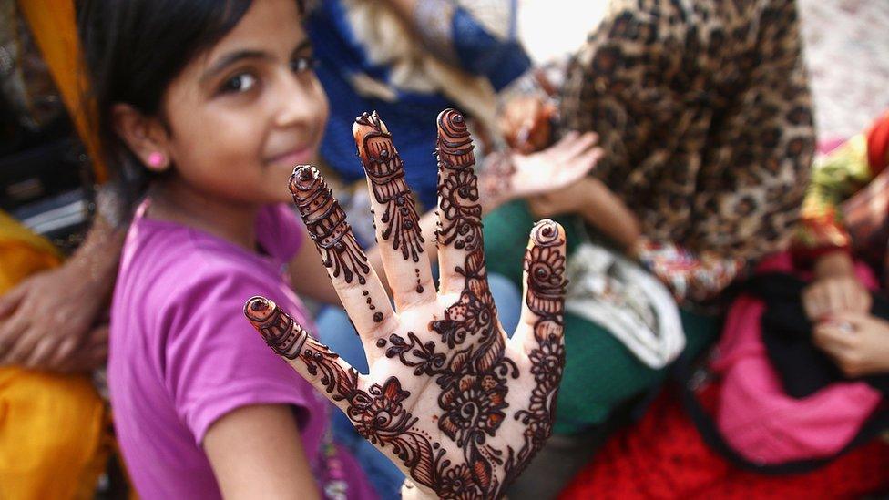 A girl shows the henna tattoo on her hand to mark the end of Ramadan, in Karachi, Pakistan.