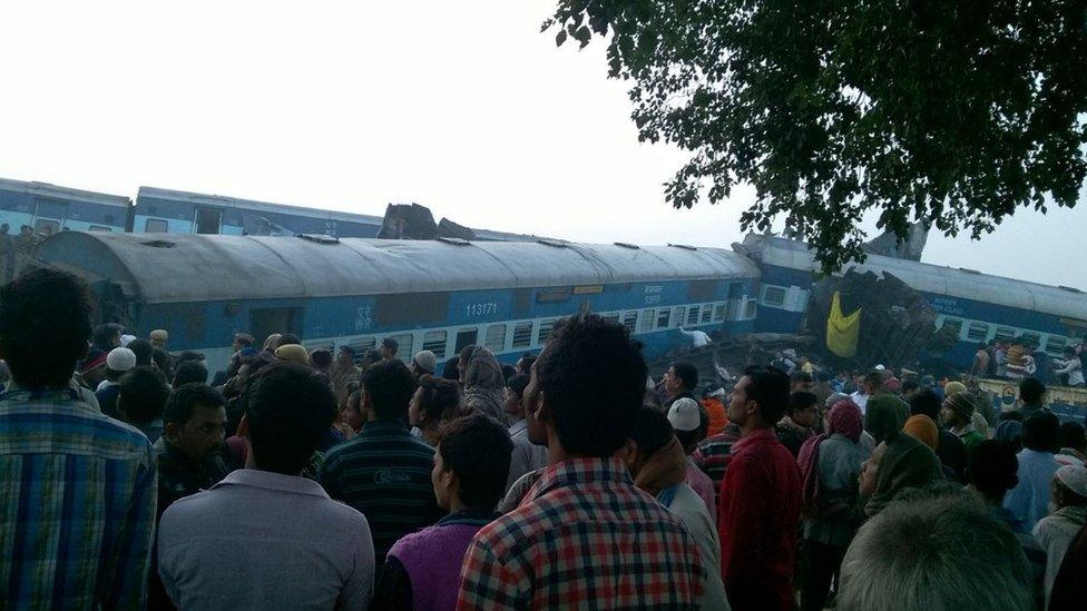 Locals look at the wreck on the derailed train