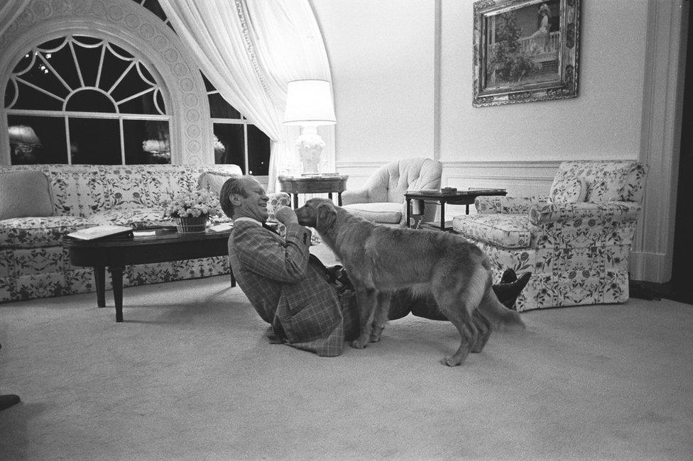 President Gerald R Ford plays with a dog in the family residence of the White House