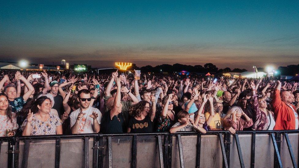 Festivalgoers at FORWARDS at the front close to the barrier with lights in the background