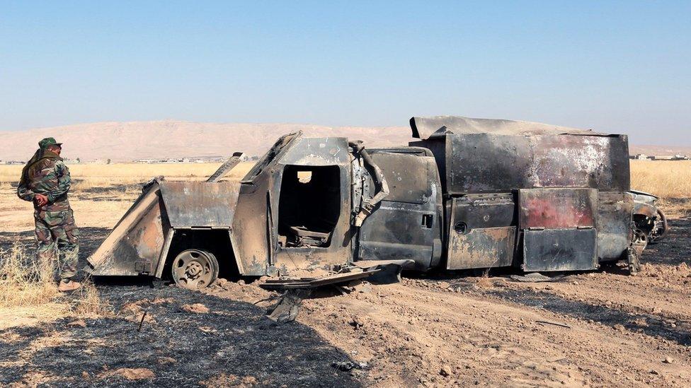 A Kurdish fighter inspects a charred truck used by Islamic State militants east of Mosul, Iraq, 18 October 2016