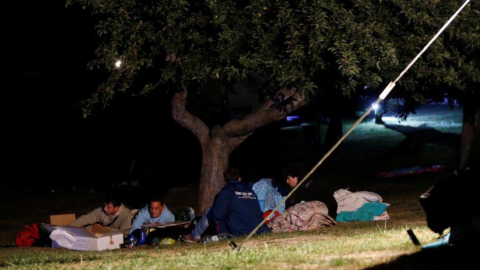 People cover themselves with blankets as they prepare to spend the night in the open following an earthquake in Amatrice