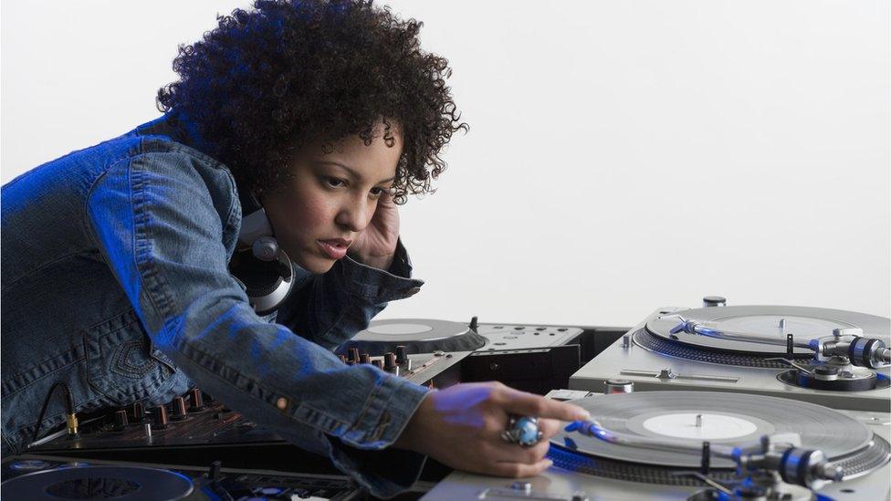 Stock image of a woman DJ-ing at a set of record decks