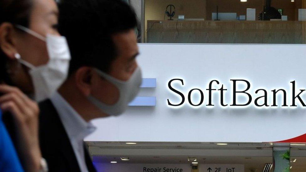 Pedestrians walk past a Japan's SoftBank mobile shop in Tokyo.