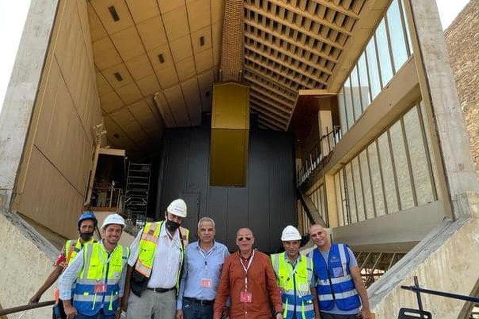 Egyptian experts and workers pose in front of the Great Boat of King Khufu