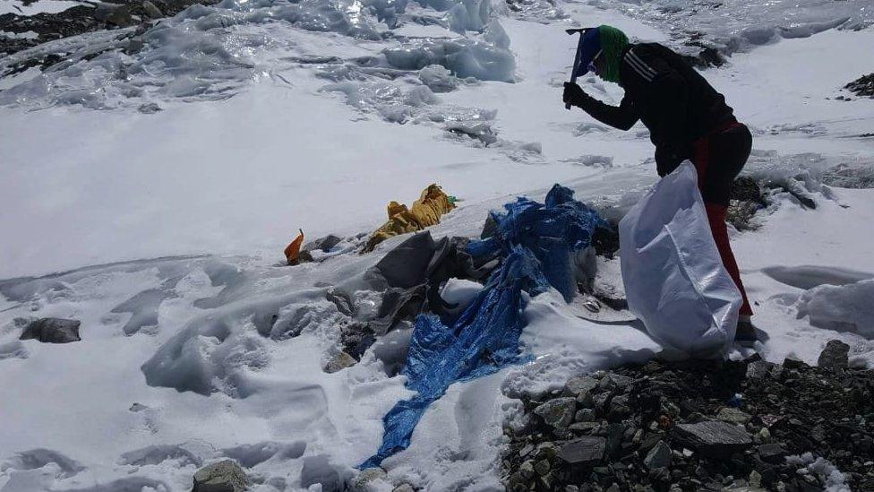 A member of a clean-up campaign clearing rubbish left behind at Camp Three