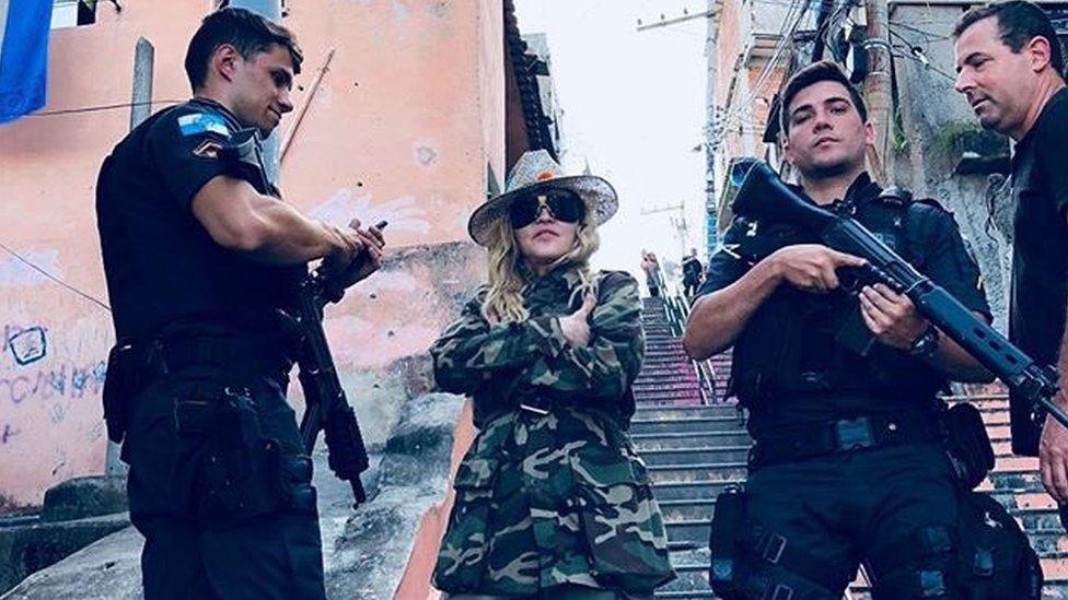 Madonna poses with military police wielding guns in a Rio de Janeiro slum.