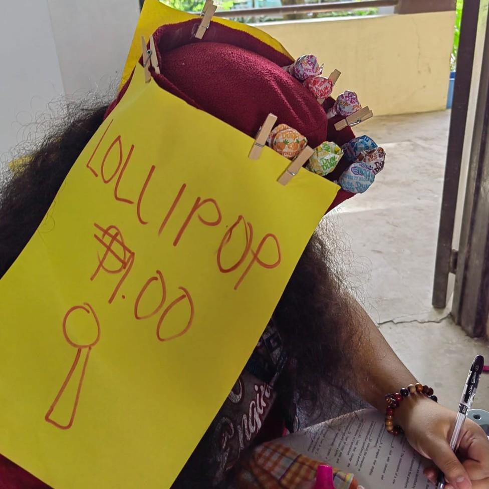 A student wears a homemade hat adorned with lollipops during a college exam in the Philippines