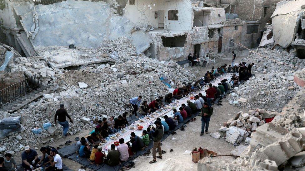 People sharing a meal provided by volunteers in a bomb- damaged neighbourhood in Atarib, outside Aleppo (May 2020)