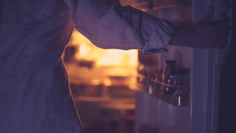 Woman standing by fridge, stock image