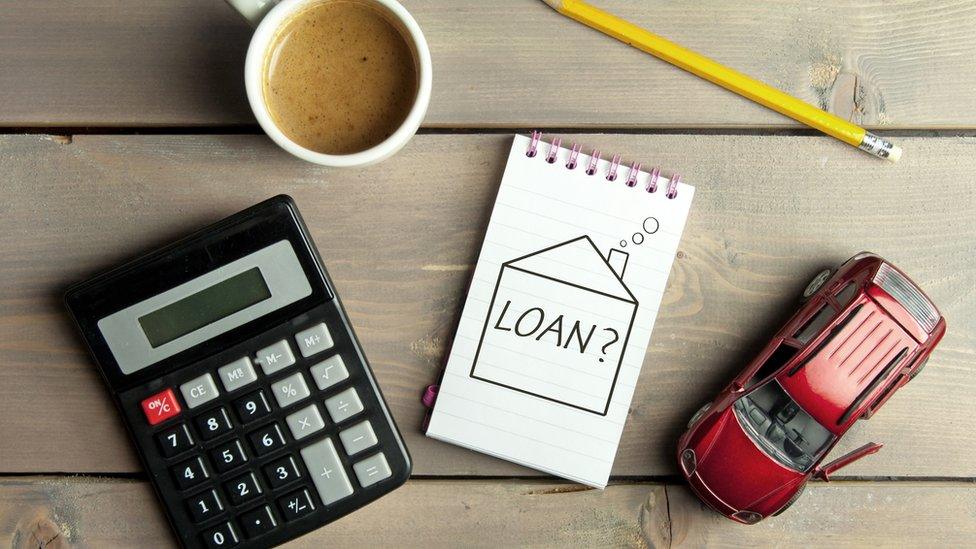 Notepad with loan question inside a sketch of a house with a miniature car and calculator