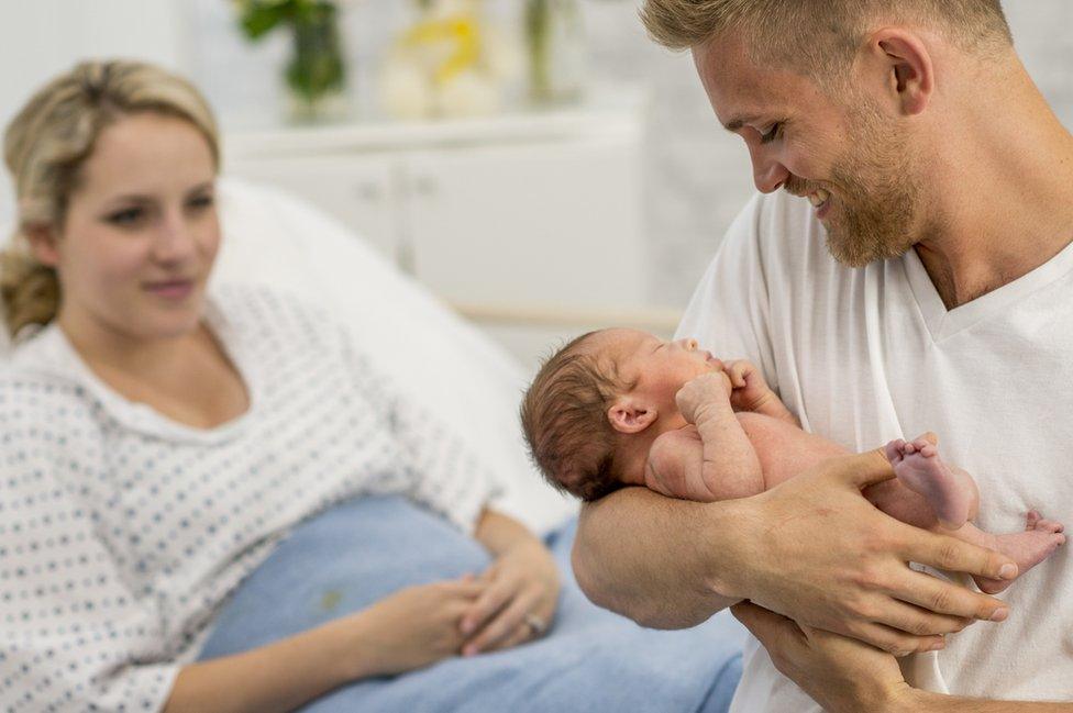 Father holds new baby in hospital