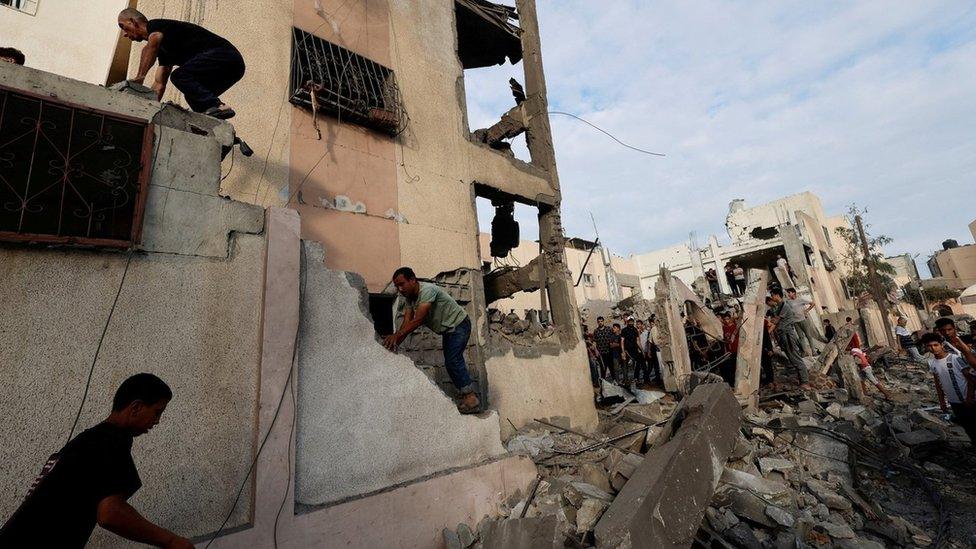 Palestinians search for casualties after homes were destroyed in an Israeli air strike in Khan Younis, in the southern Gaza Strip (17 October 2023)