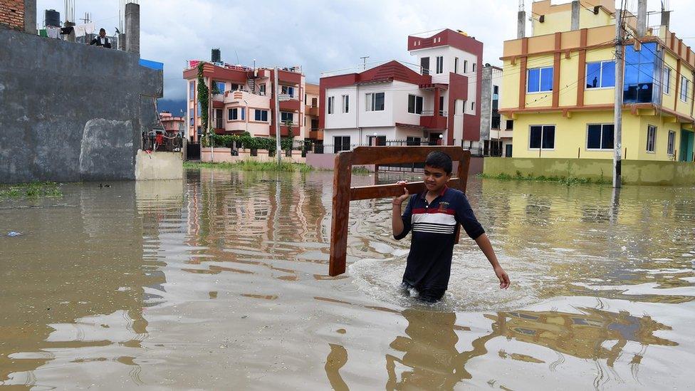 Nepali youth carries home goods along a water logged street in Patan, on the outskirts of Kathmandu