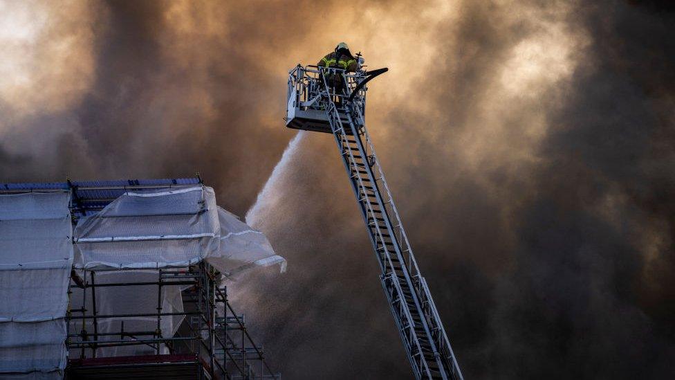 A firefighter tries to extinguish flames at the historic Boersen Stock Exchange in Copenhagen on Tuesday, April 16, 2024