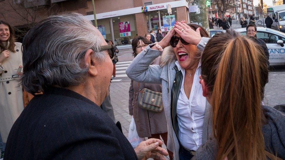 People celebrate outside the lottery office giving the El Gordo (The Fat One) prize, in Madrid, Spain