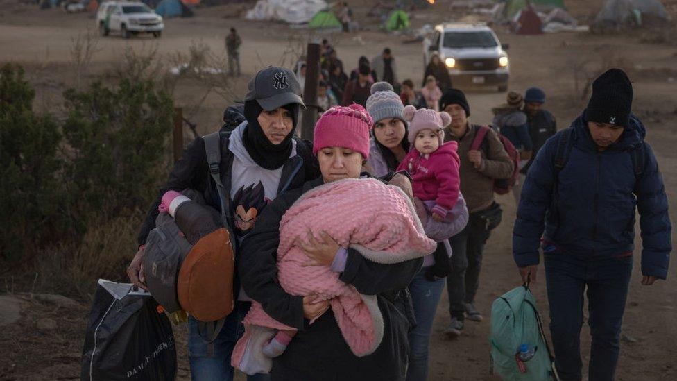 Asylum seeking migrants wait to be processed by the US Border Patrol after crossing from Mexico at a makeshift camp next to the US border wall on December 13, 2023 in Jacumba Hot Springs, California