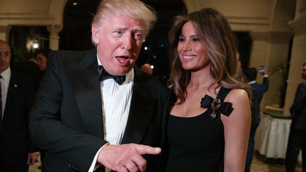 Melania Trump, right, looks on as her husband President-elect Donald Trump talks to reporters during a New Year"s Eve party at Mar-a-Lago, Saturday, Dec. 31, 2016, in Palm Beach,