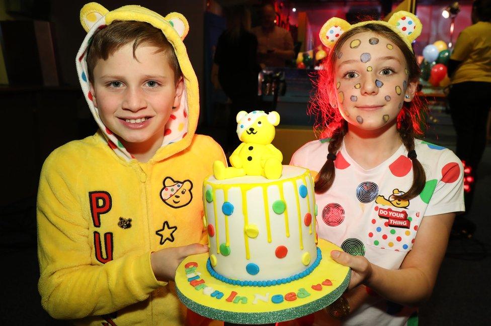 Two children hold a Childern in Need themed cake