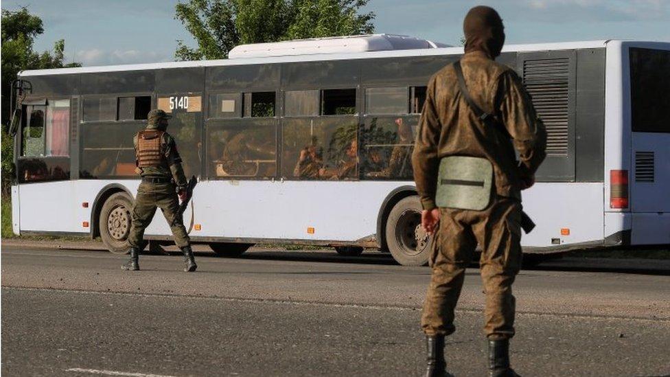 Russian-backed soldiers guard a bus with Ukrainian soldiers outside Mariupol, south-eastern Ukraine. Photo: May 2022