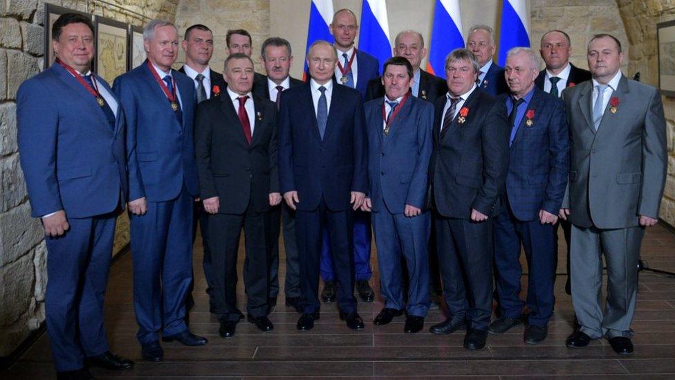 President Vladimir Putin (C) poses with participants in a ceremony to present state decorations at the Konstantinovskaya Batareya [Konstantin Battery] Museum and Exhibition Centre