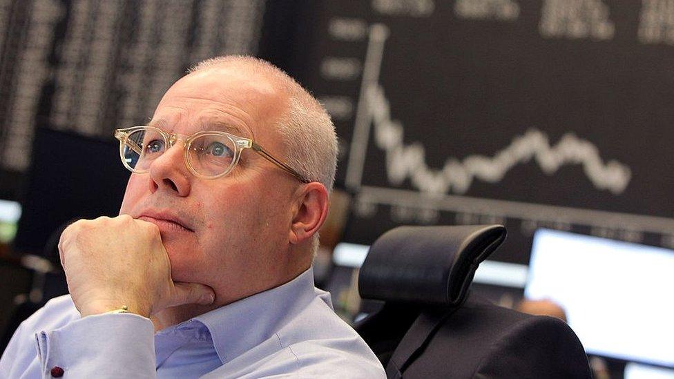 A trader looks up at the board displaying the day's course of the DAX stock market index at the Frankfurt Stock Exchange