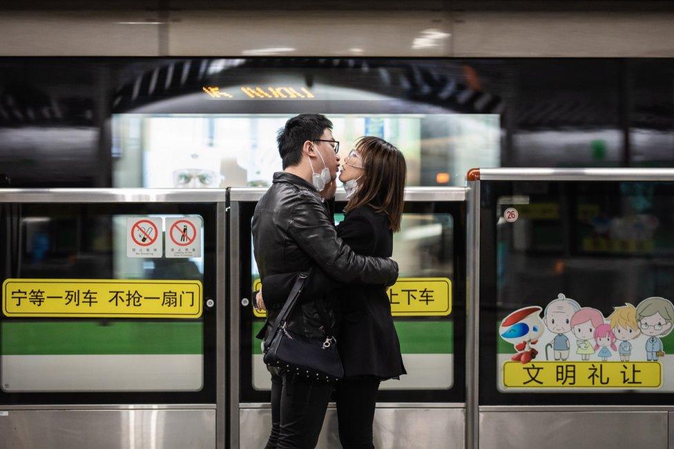 A couple kiss each other with their masks off while waiting for a train in Shanghai. 24 February