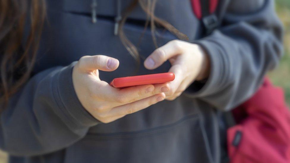 Mobile phone in hands of unrecognizable young girl close-up outside, modern tehnology