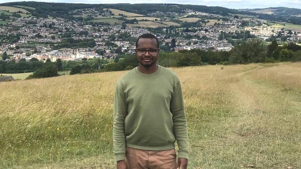 Ukrainian Excel wearing a green jumper with Gloucestershire countryside behind him and blue skies