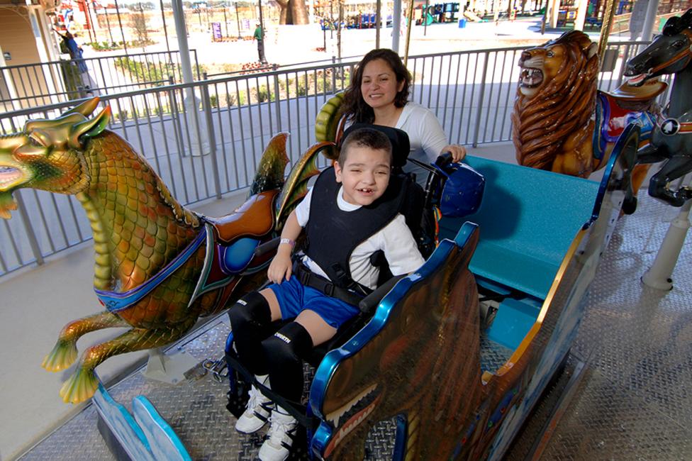 A young boy in a wheelchair enjoys the carousel