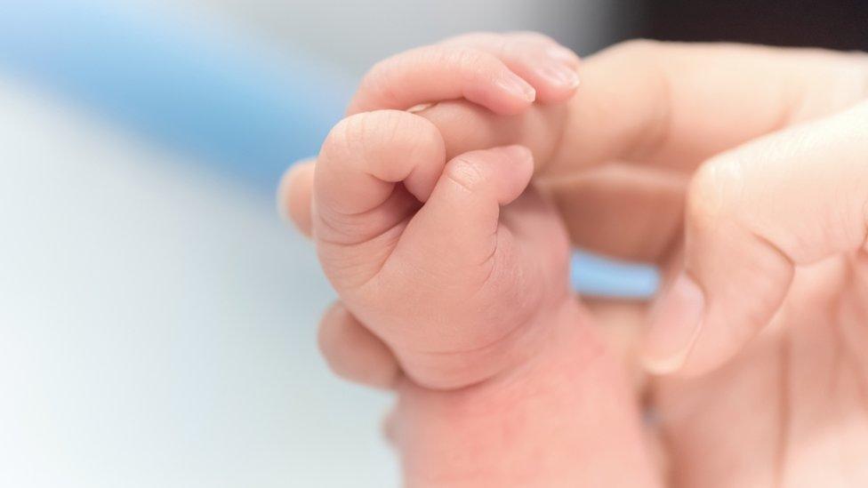 A mother holds a baby's hand