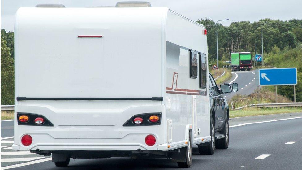 A caravan being towed by another vehicle, on the motorway.