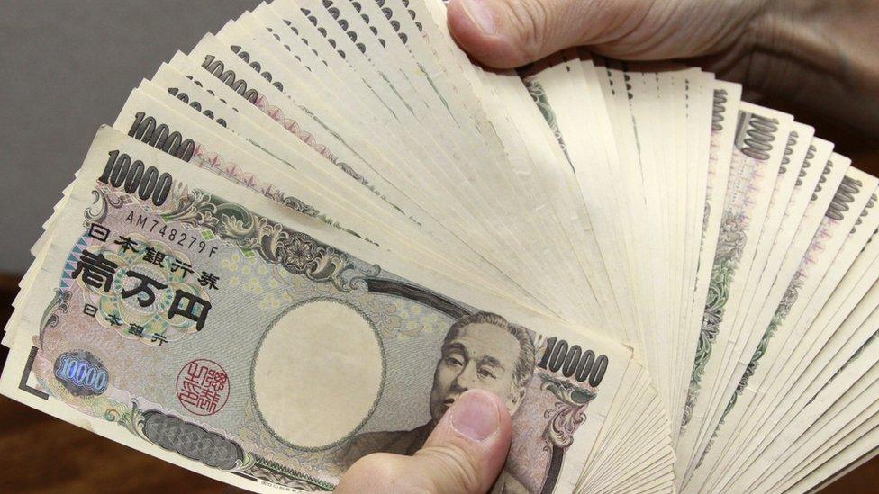 A man holds a pile of 10,000 yen notes.