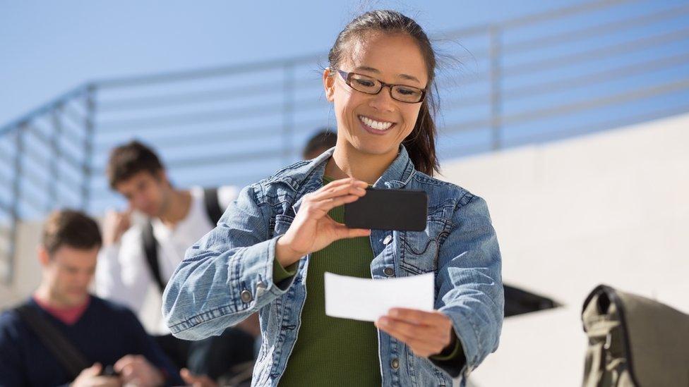 A woman takes a picture of a cheque