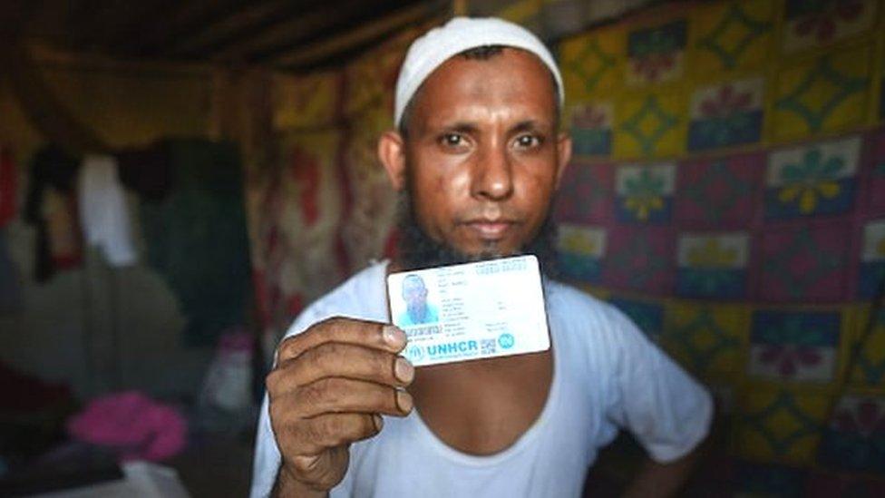 A refugee living at the Rohingya refugee camp holds up his UNHCR card at Kalindi Kunj on August 17, 2022 in New Delhi.