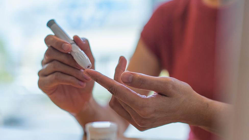 A person takes a finger prick blood test at home