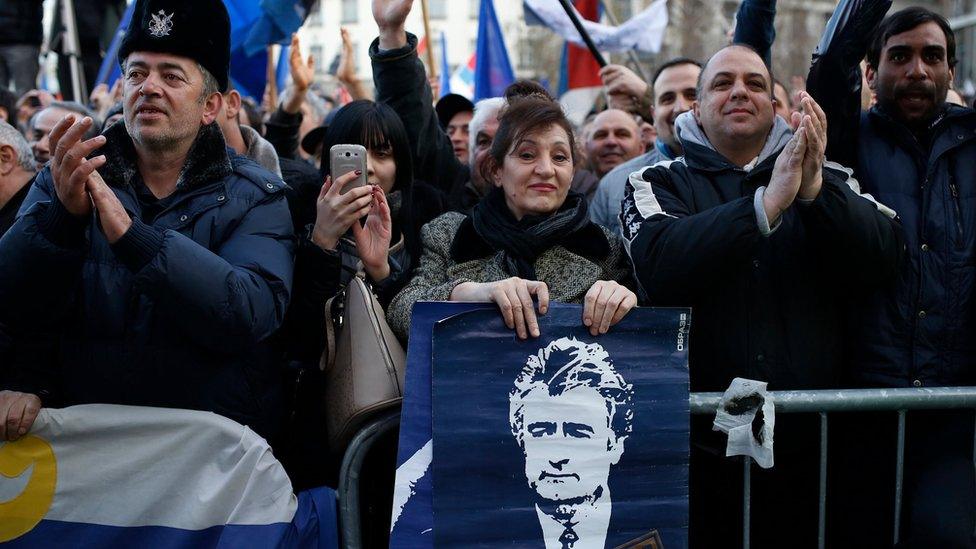 A supporter of Serbian ultra-nationalist leader Vojislav Seselj holds a placard depicting Bosnian Serb wartime leader Radovan Karadzic during an anti-government rally in Belgrade on 24 March 2016.