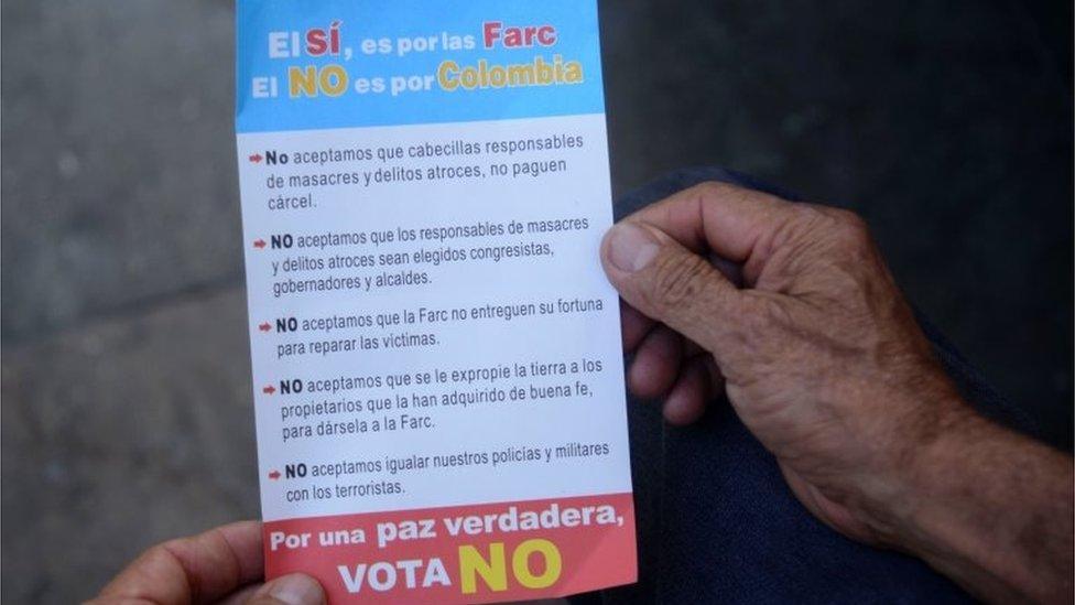 A Colombian peddler holds a leaflet against the ratification of a historic peace accord between the Colombian government and the FARC guerrilla reading "YES if for the FARC, NO is for Colombia. For real peace vote NO" in Medellin, Antioquia department, Colombia on October 3, 2016.