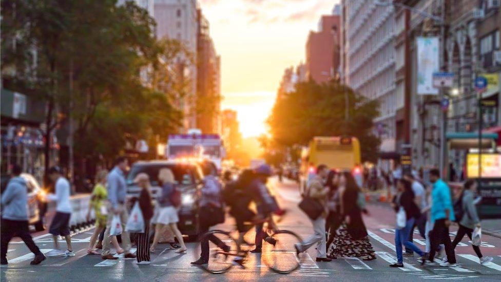 Crowds of people cross a busy intersection on 23rd Street and 6th Avenue in Manhattan