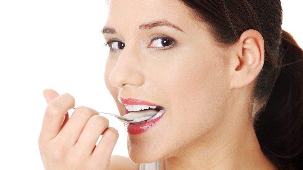 Woman eating yogurt, stock image