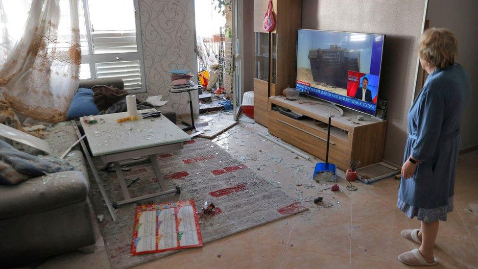 An Israeli woman reacts as she checks the damage inside her house hit by Palestinian rocket fire in the southern city of Ashkelon