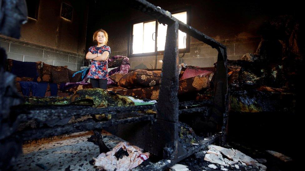 A girl looks at the damage to the home of the Dawabsha family in Duma, in the occupied West Bank, which was targeted in an arson attack (11 May 2018)