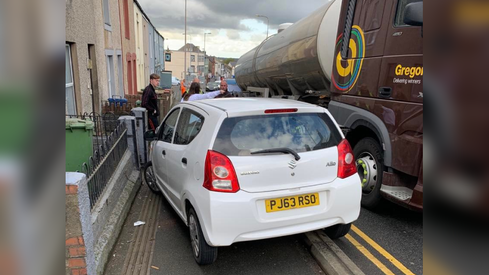 A car on the pavement following a collision with a truck on the A487