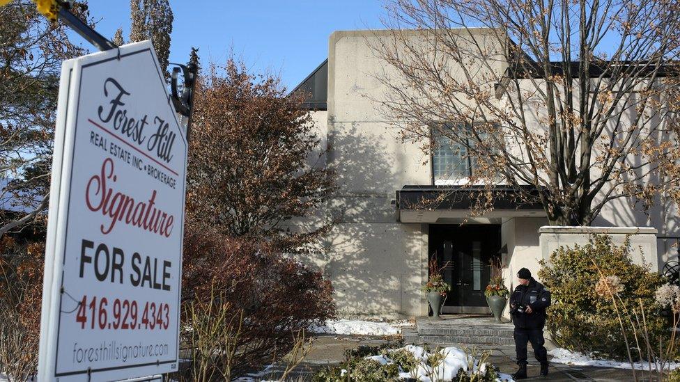 A police forensics photographer works outside the home of billionaire founder of Canadian pharmaceutical firm Apotex Inc. in Toronto