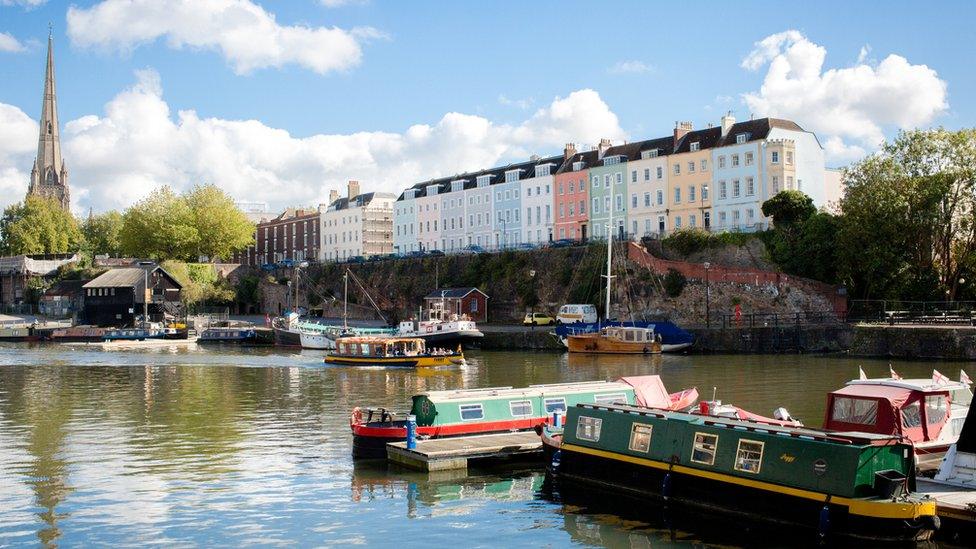 Boats on Bristol Floating Harbour with colourful houses in backdrop