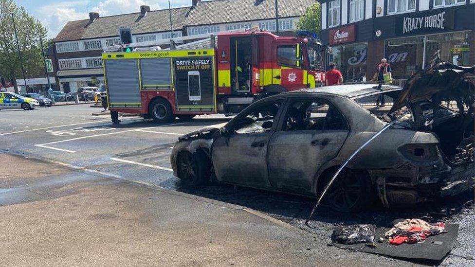 The burnt out car next to the fire engine