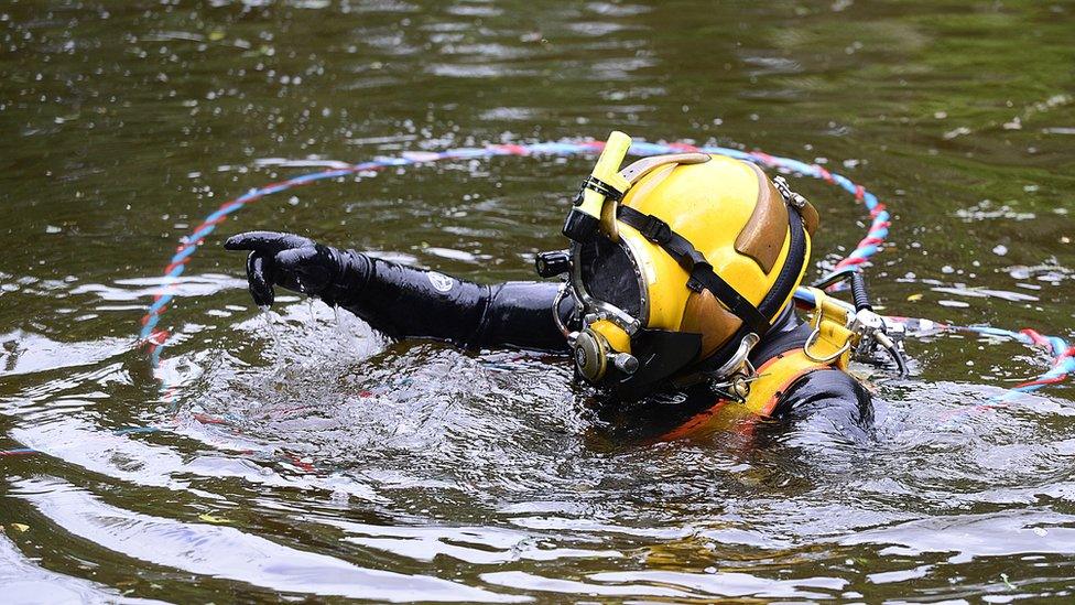 A police diver enters the lake as part of the search